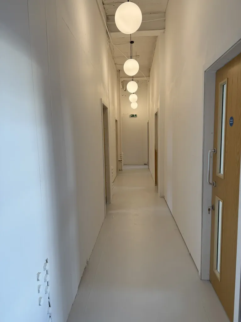 The corridor to the studio workshops at Hone Tottenham, with globe lights and oak doors