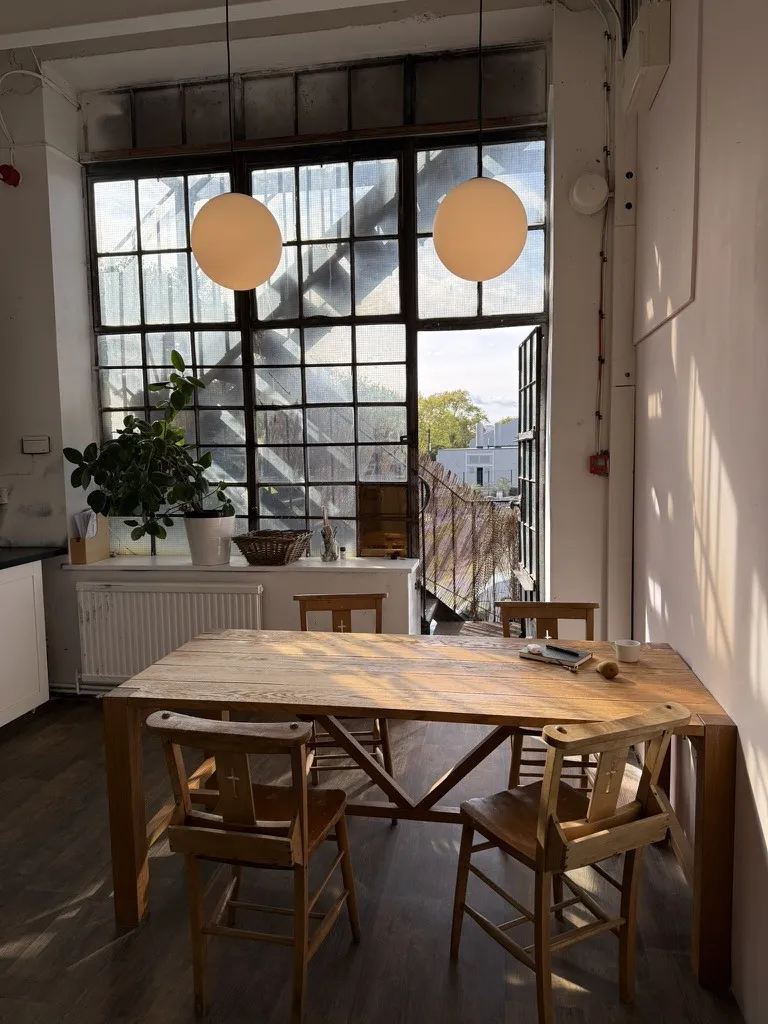 The shared kitchen at Hone Tottenham, its long table under a wall of windows